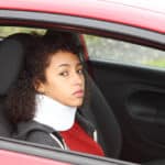 female wearing neck brace in car-whiplash insurance theme