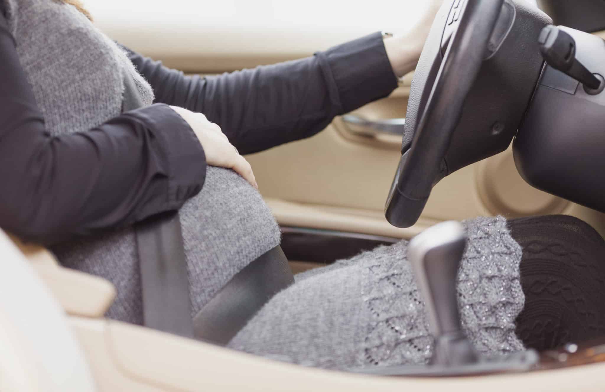 Pregnant woman driving a car with one hand