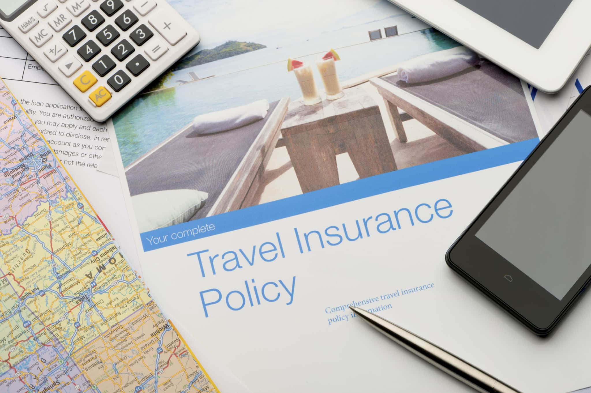 Travel insurance policy document with paperwork and technology. There is an image of a tourist resort with cocktails and a swimming pool which adds to the peace of mind concept. There is also a mobile phone, map, digital tablet and calculator. Image featured on the brochure can be found in my portfolio 20943516